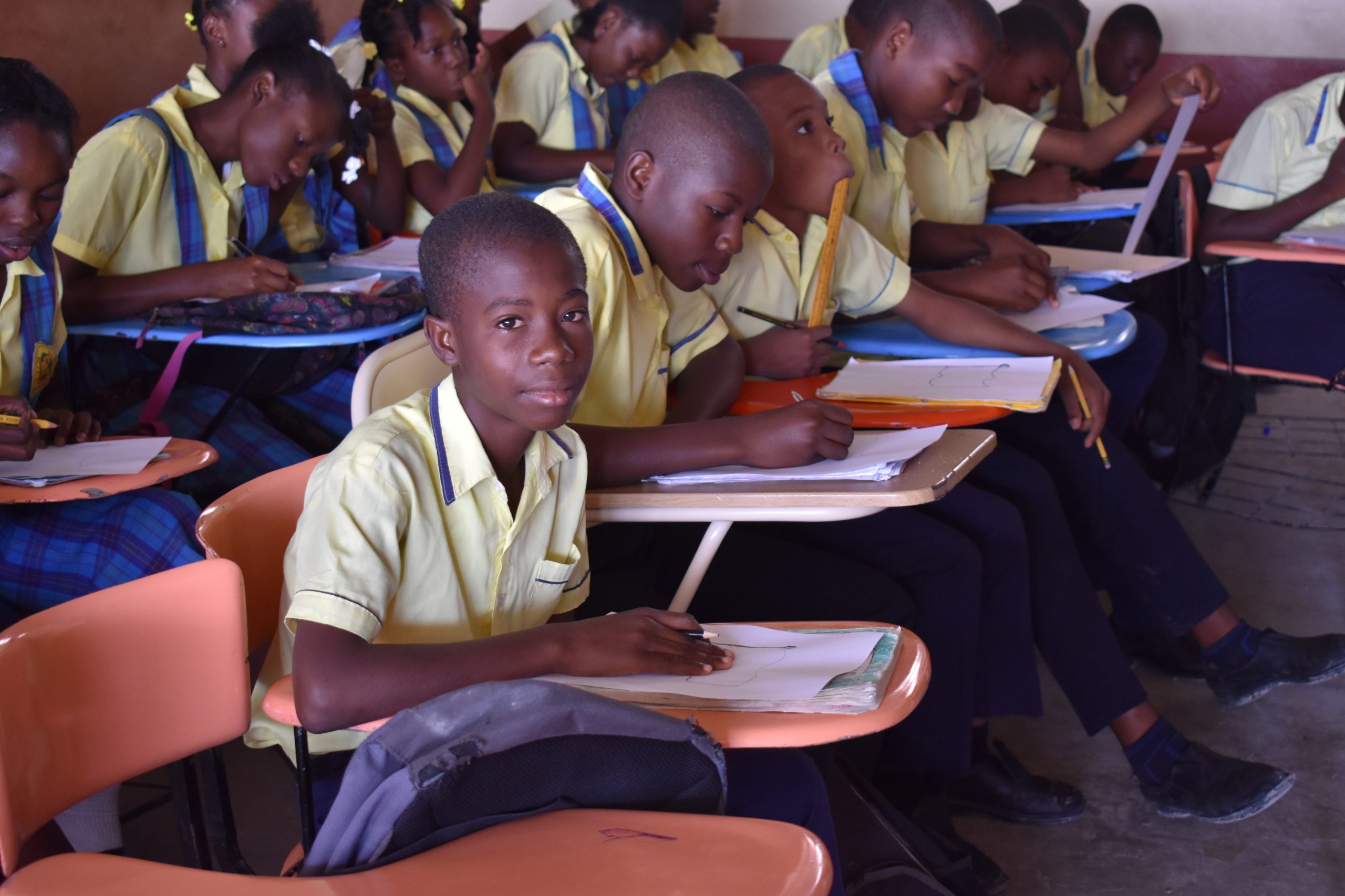 Students attentively writing in notebooks during class.