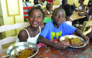 Two children enjoying a meal together at a table.