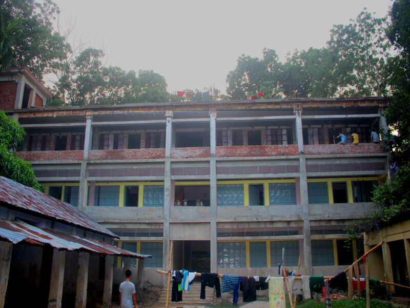 Three-story building with people and laundry outside at dusk.