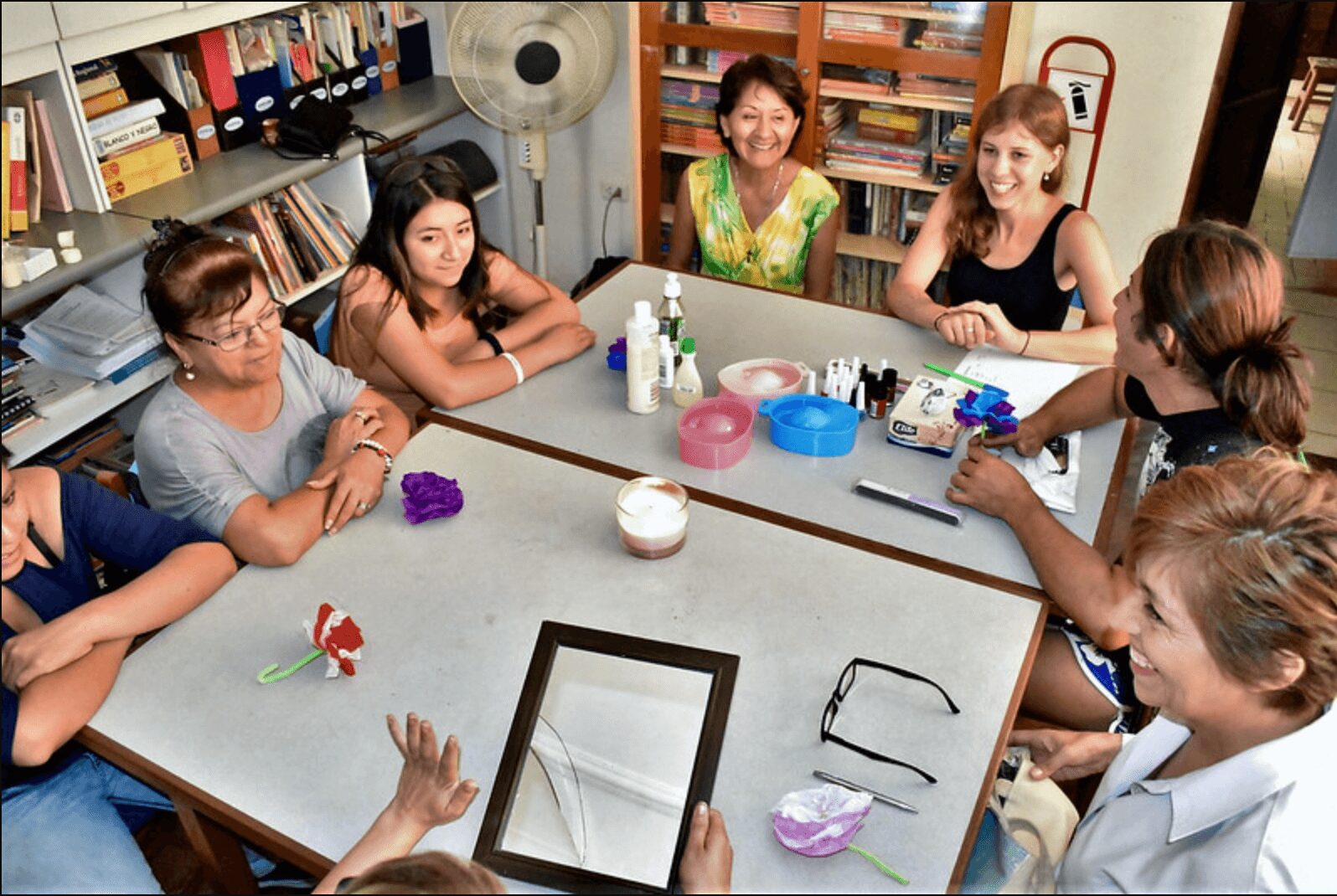 Five adults gathered around a table in a cozy room, engaging in an art or craft activity.