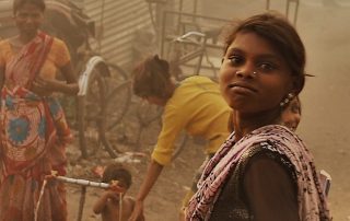 A young girl in a bustling, smoky street market.