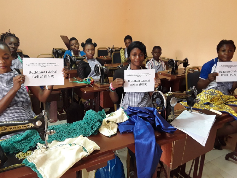 Women showcasing handmade textile products in a classroom setting.