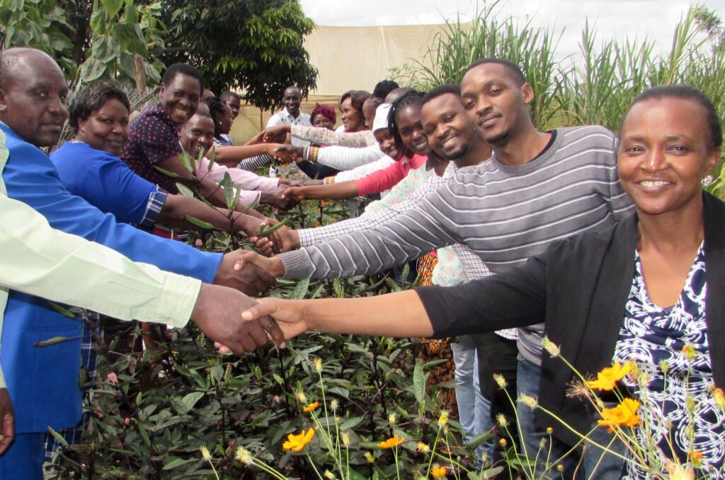 People shaking hands over a table covered with greenery and flowers.