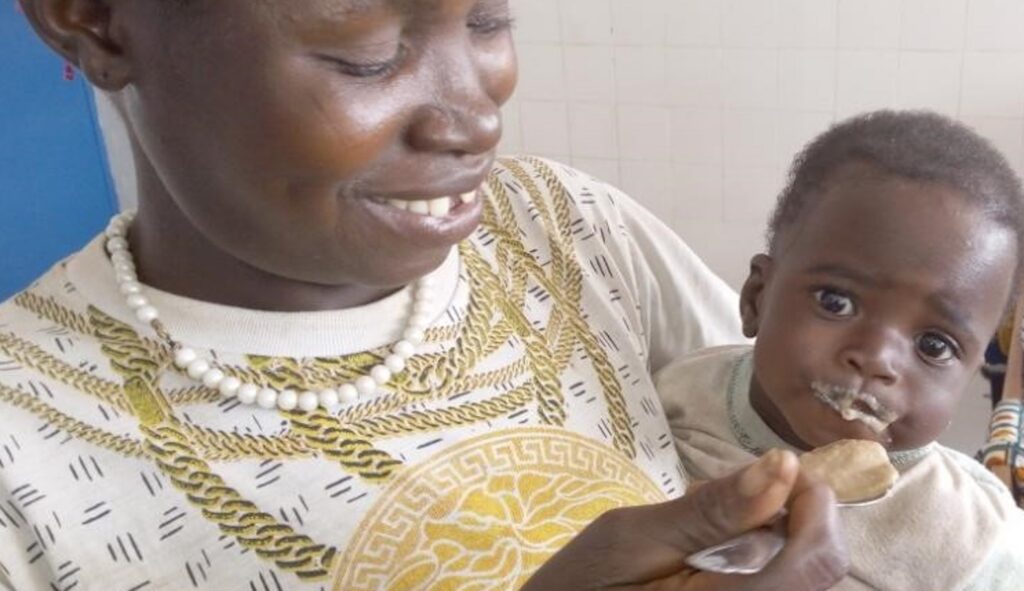 A smiling woman holding a baby close to her chest.