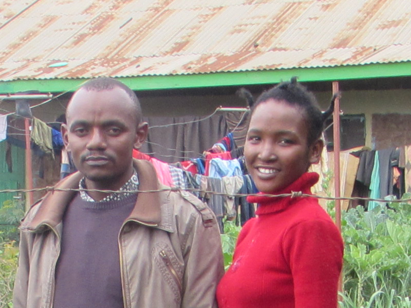 Two people standing outdoors near a building with a rusty roof. Two people standing outdoors near a building with a rusty roof.