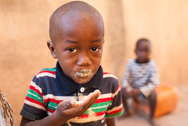 Young boy eating with hands, focused on food.