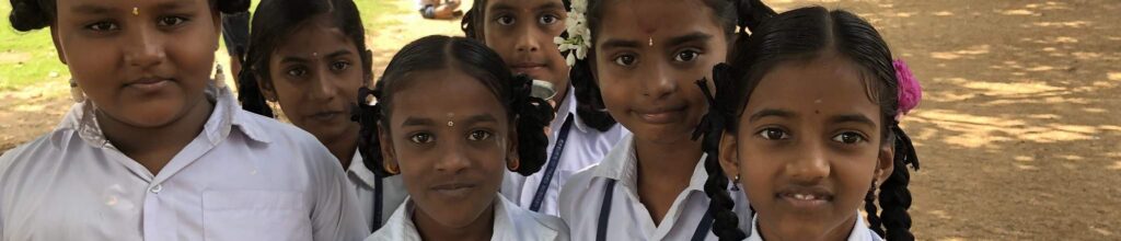 Three young girls in school uniforms posing together.