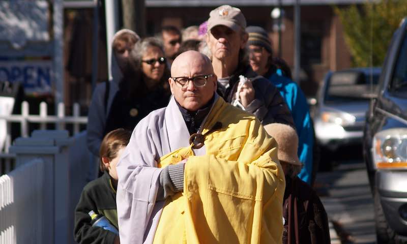 A man in ceremonial robes holds a golden cloth during a public event. A man in ceremonial robes holds a golden cloth during a public event.