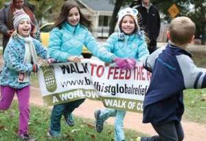 Four young children are joyfully holding the Walk to Feed the Hungry banner