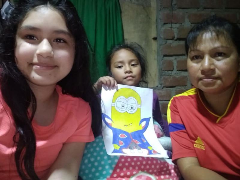 Three children holding a colorful drawing of a Minion character.
