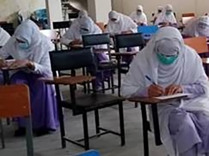 Students wearing masks taking an exam in a classroom.