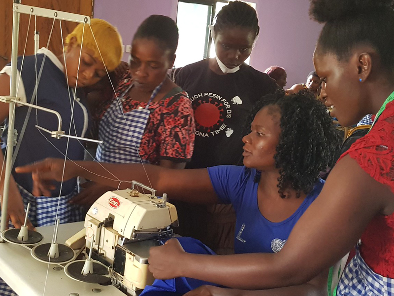 Women learning to sew with a sewing machine in a group setting.