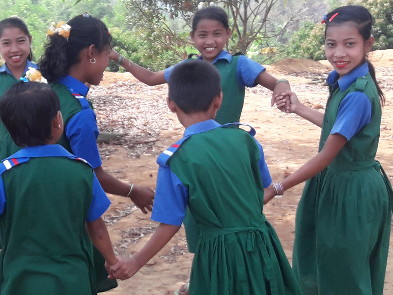 Children in school uniforms holding hands outdoors.
