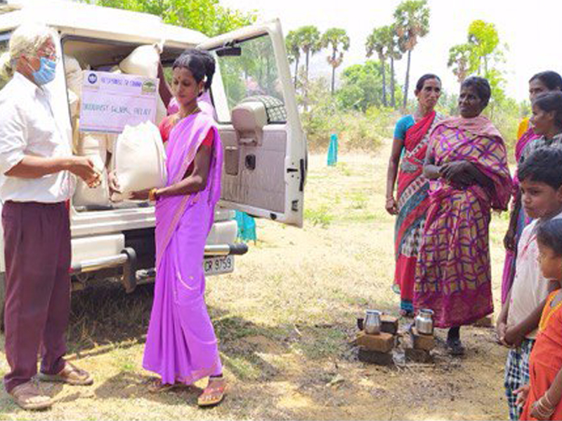 Women in vibrant sarees engaged in outdoor activity with containers.