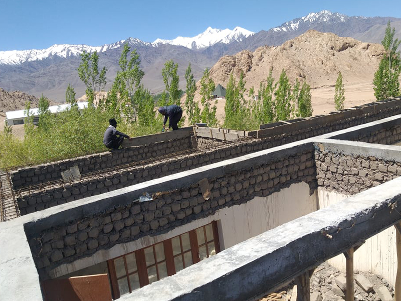 Construction workers building a stone structure in a mountainous area.