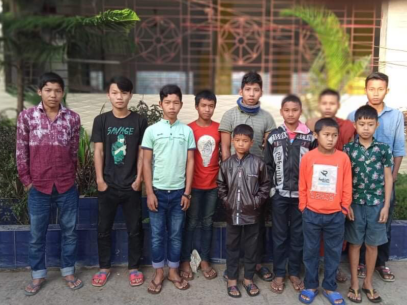A group of boys standing outdoors in casual clothes.