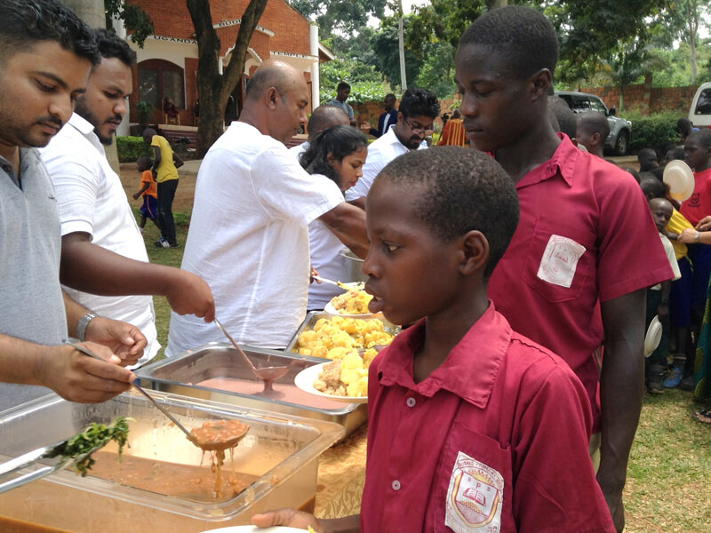 Children receiving food from volunteers in an outdoor setting.