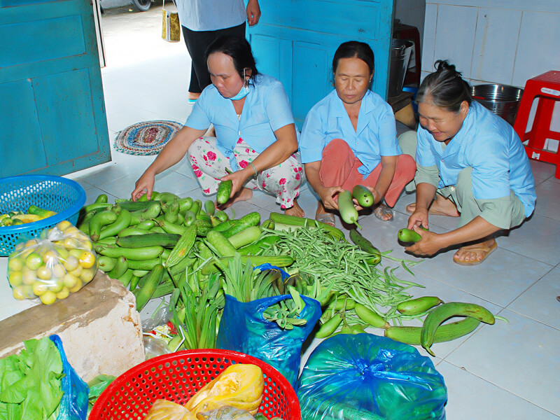 Three women preparing fresh vegetables together indoors.