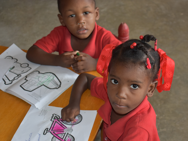 Two children coloring in a book, focused and engaged.