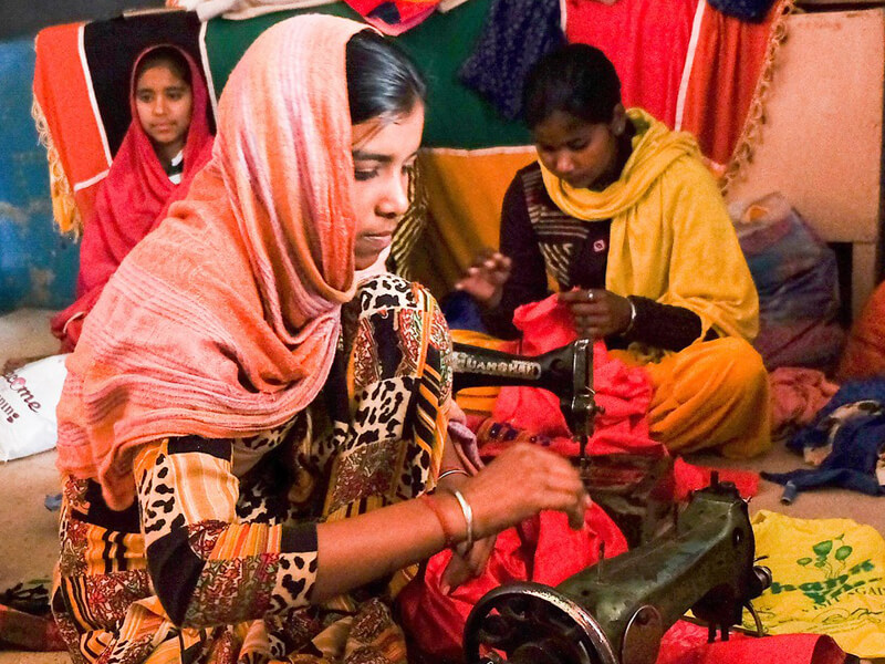 Women sewing and working with fabric in a vibrant setting.