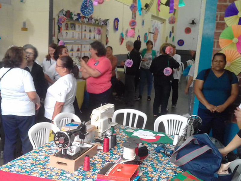 People gathered at a colorful indoor celebration with decorated tables and hanging ornaments.
