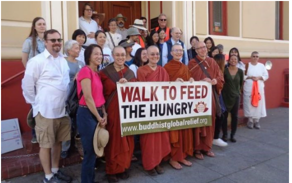 Group holding a banner for a Buddhist charity event.
