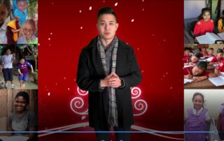 Young man in a black coat and scarf standing against a red festive background.
