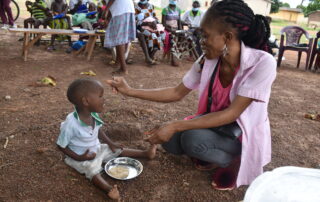 A midwife feeds a malnourished child at a site in northern Cote d'Ivoire.