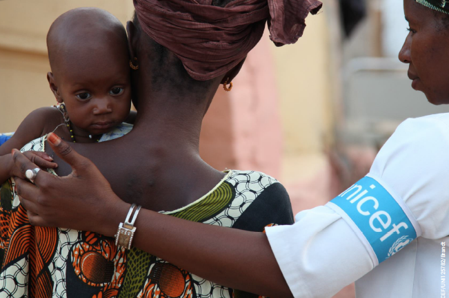 A woman from the Horn of Africa is holding her kid with the helping hand from BGR partner UNICEF