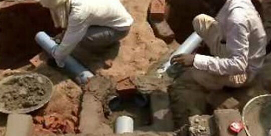 Two men are working on the ground for the pipe system