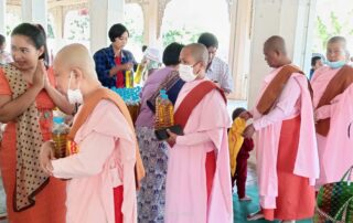 Five novice nuns in Myanmar surrounded by laypeople during meal dana offering