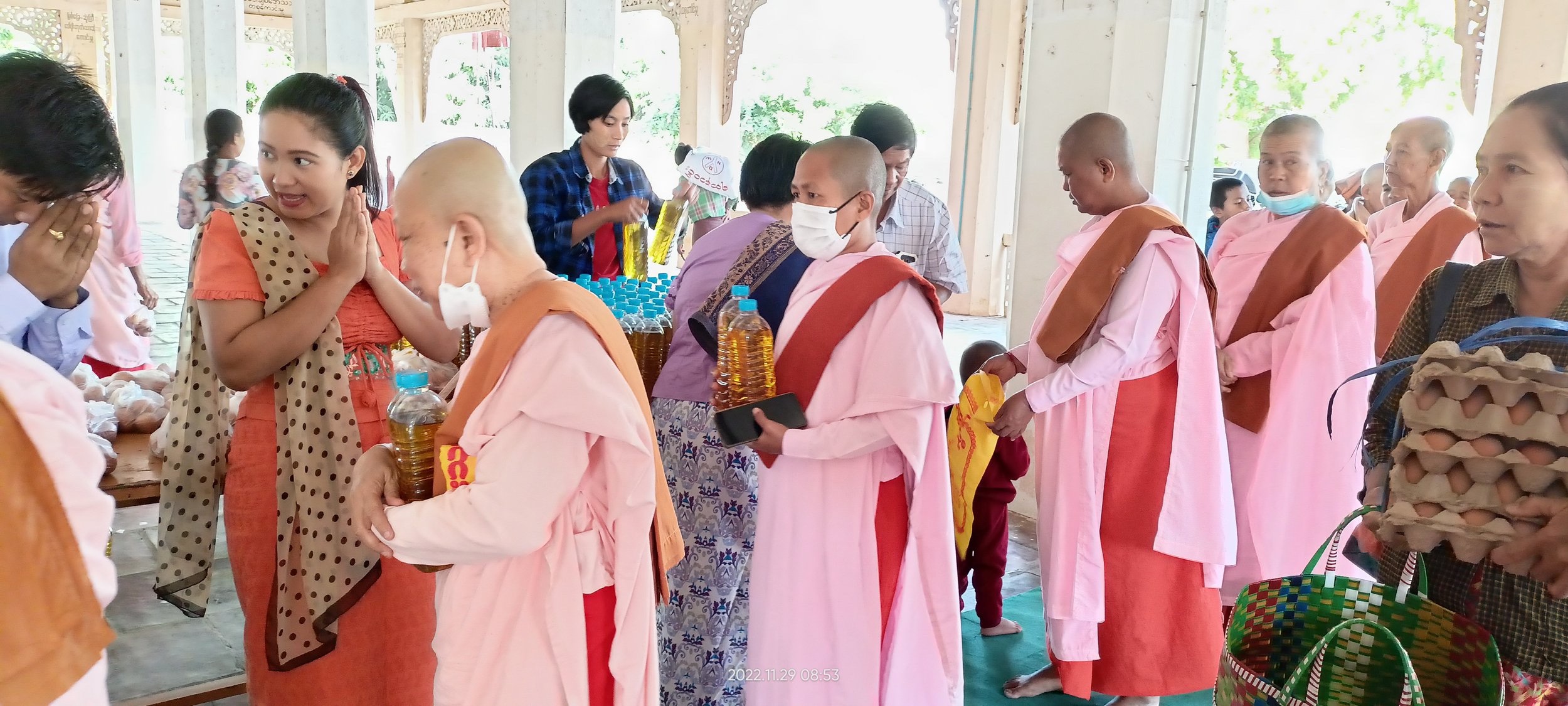 Five novice nuns in Myanmar surrounded by laypeople during meal dana offering