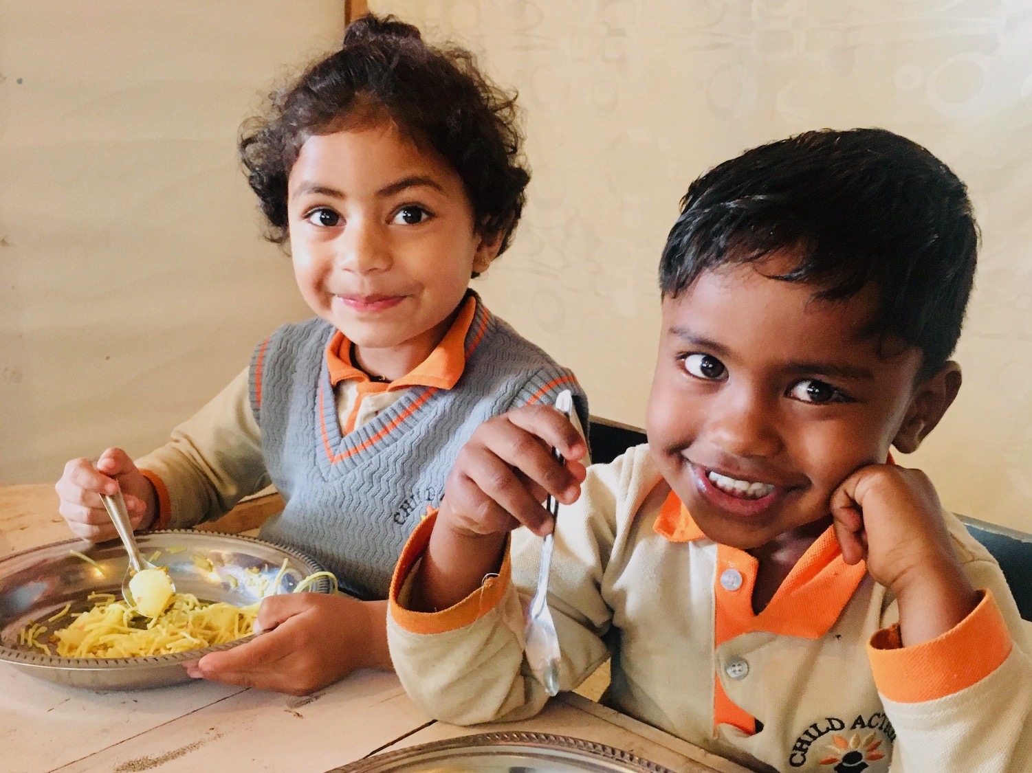 Two Sri Lankan children smiling and eating a healthy breakfast.