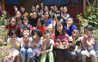 Children at the Mahabodhi Tawang school happily eating apples