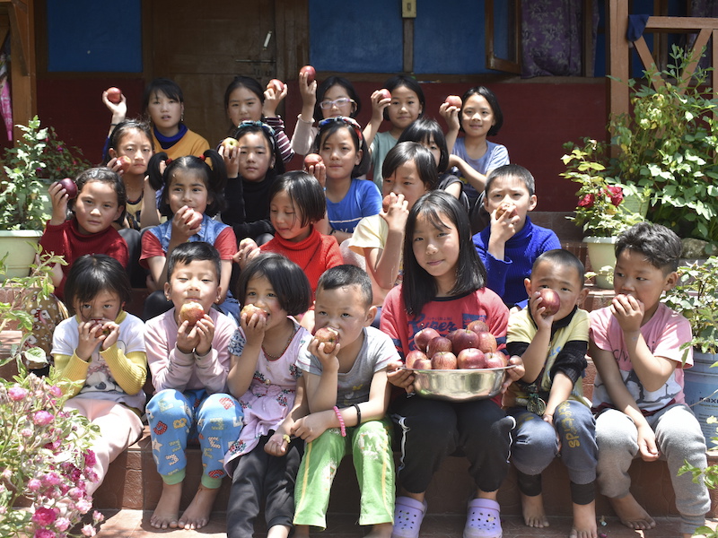 Children at the Mahabodhi Tawang school happily eating apples