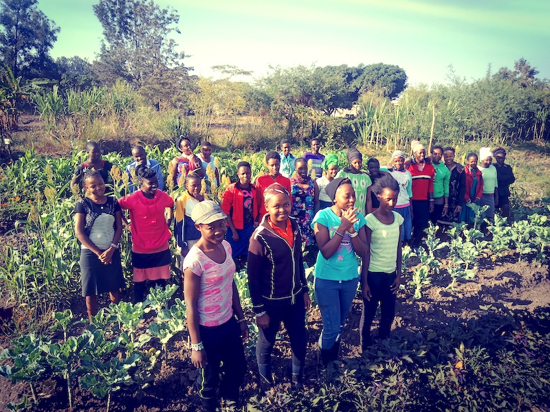 Students at G-BIACK stand together in a community garden.