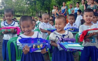 Smiling children in a Myanmar IDP camp show the camera their new schoolbooks.