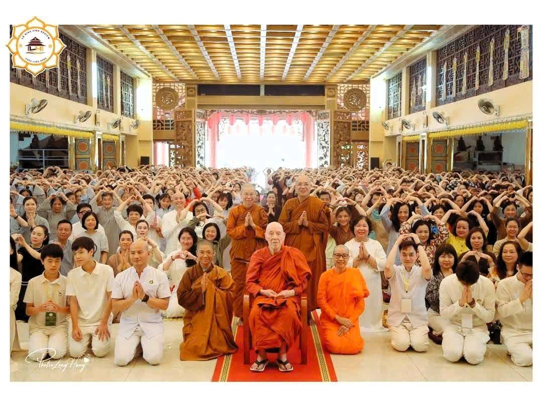 A large group gathered around monks in a ceremonial hall.