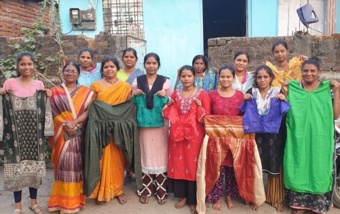 A group of women standing together, some holding shawls, outdoors in front of a building.