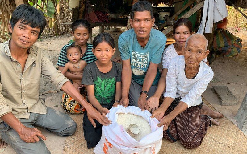 A group of people presenting a large fish wrapped in cloth.