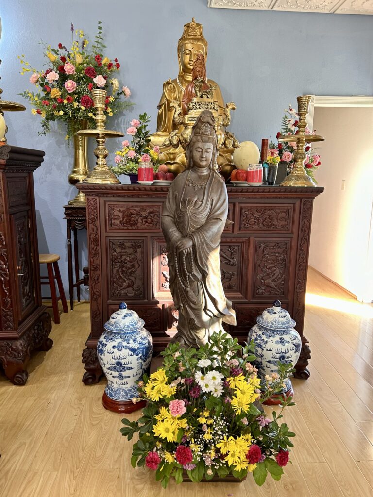 Buddhist altar with statues and floral arrangements.