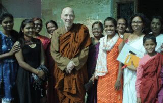 Group smiling with a monk in orange.