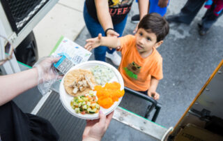 A child reaches for a meal offered by the Capitol Area Food Bank.
