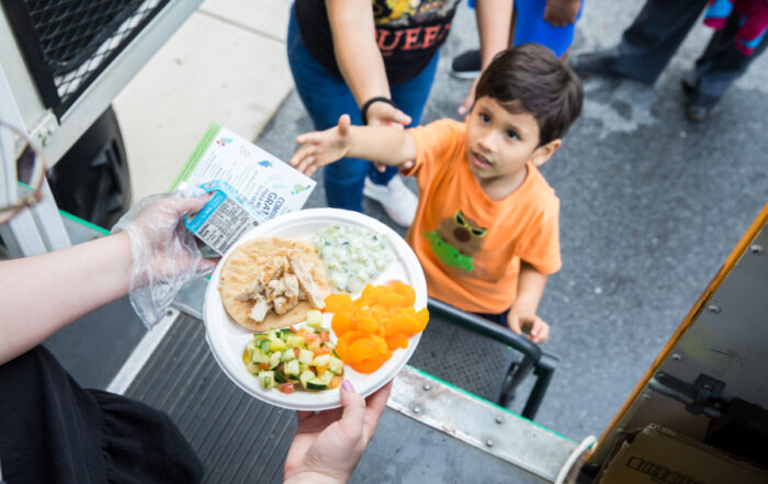 A child reaches for a meal offered by the Capitol Area Food Bank.