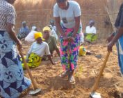 A group of women observe an agricultural demonstration in Malawi.