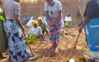 A group of women observe an agricultural demonstration in Malawi.