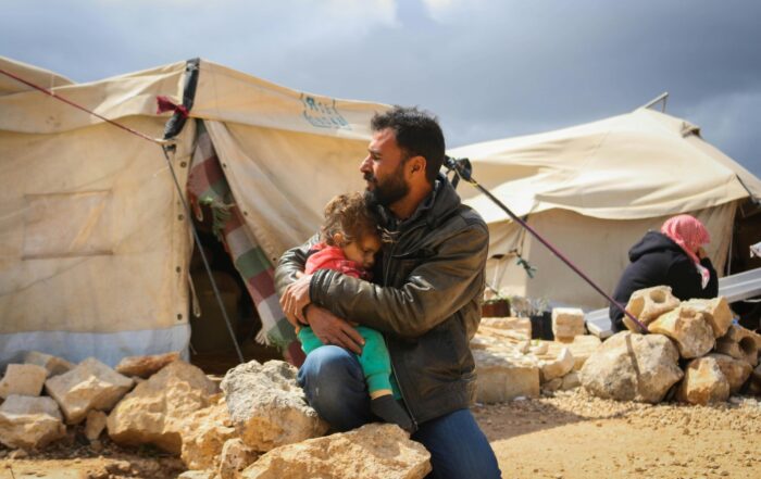 A man embraces a child at an IDP camp in Syria.