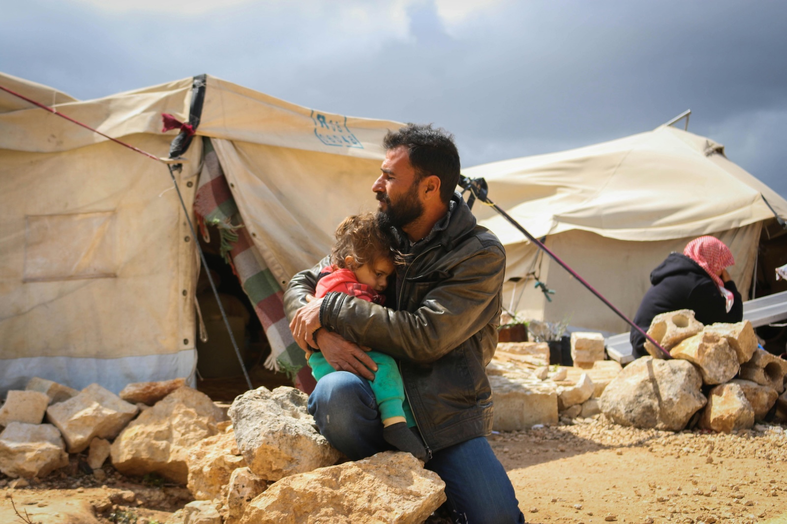 A man embraces a child at an IDP camp in Syria.